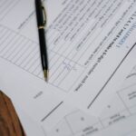 A detailed view of graded test papers with a pen resting on a wooden desk.