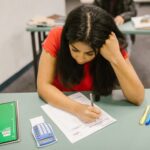 A focused college student studying at her desk during an exam preparation session.